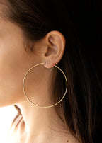 A close-up image of a person wearing a large gold hoop earring.